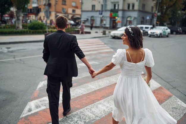 Auf dem Zebrastreifen Schöne Braut mit ihrem Verlobten feiert Hochzeit im Freien