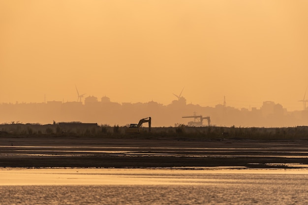 Auf der Baustelle scheint morgens die Sonne golden und ein Bagger arbeitet