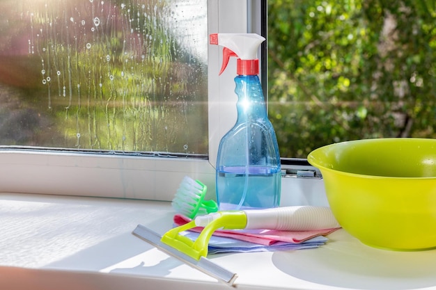 Auf der Fensterbank stehen Fensterputzwerkzeuge und Reinigungsmittel