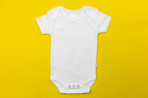 Auf der gelben Oberfläche lag ein weißes Baby-Bodysuit-Modell