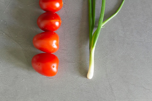 Auf der grauen Arbeitsfläche der Küche liegen frische Tomaten und Frühlingszwiebeln aus dem Garten