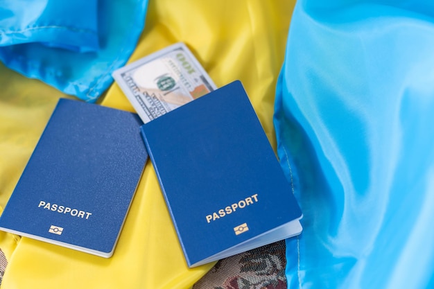 Auf der Nationalflagge der Ukraine liegt gelb-blau ein biometrischer Auslandspass mit Geld.