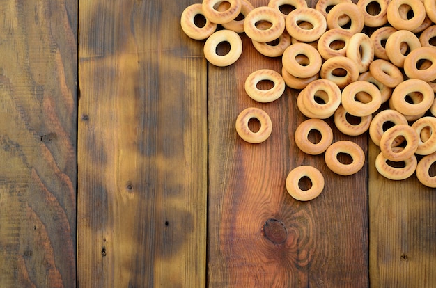 Auf der Oberfläche des alten dunklen Holzes liegen viele frische gelbe Bagel