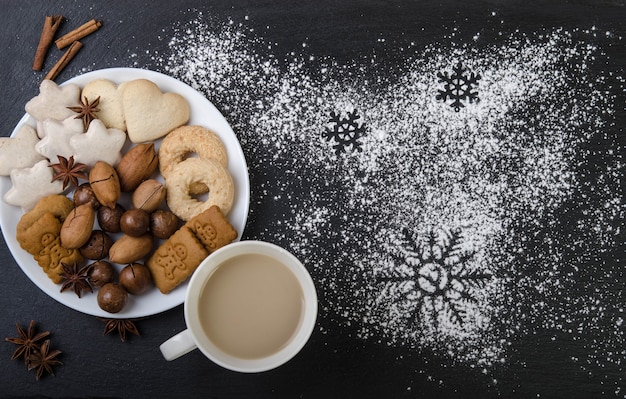 Auf der schwarzen Oberseite befindet sich ein weißer Teller mit Lebkuchen, Nüssen und einer Tasse Kakao