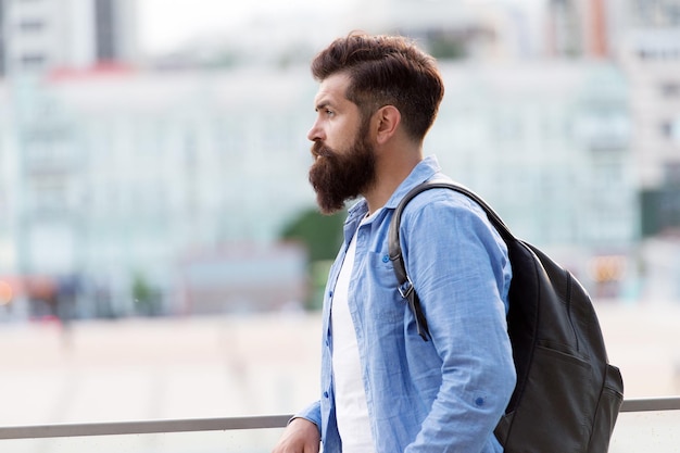 Auf der Suche nach Abenteuern. Touristischer hübscher nachdenklicher Hipster-Rucksack. Mann mit Bart und Rucksack erkunden die Stadt. Reisekonzept. Tourist im Urlaub. Hipster moderner touristischer urbaner Hintergrund.