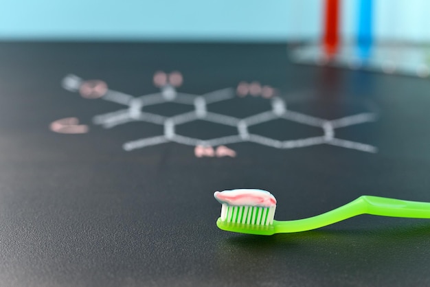 Foto auf die zahnbürste aufgetragene zahnpasta auf einem hintergrund der chemischen formel