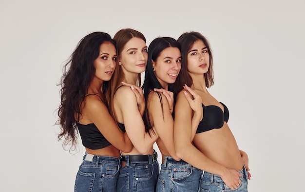 Auf einander lehnend Vier junge Frauen in der Wäsche zusammen zuhause Weißer Hintergrund