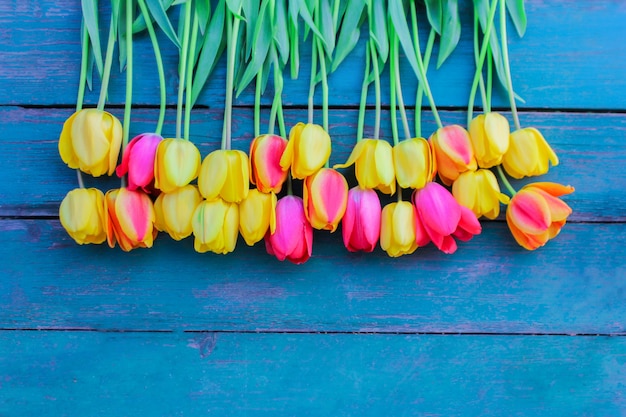 Foto auf einem blaugrünen holztisch liegt ein strauß mehrfarbiger tulpen. konzept der frühlingsstimmung und romantischen stimmung. der blick von oben.