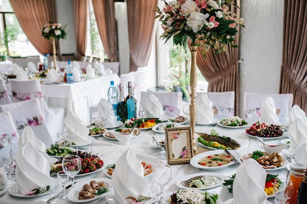 Auf einem festlich gedeckten Tisch im Hochzeitsbankettsaal steht eine Komposition aus Blumen und Grün