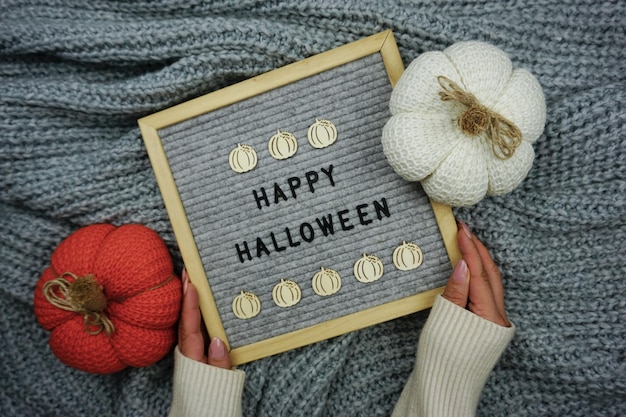 Auf einem gestrickten grauen Hintergrund ein Schild mit der Aufschrift - Happy Halloween