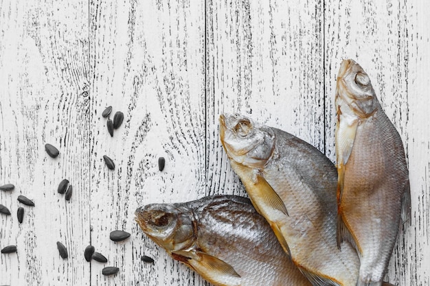 Auf einem hellen Holztisch liegen drei getrocknete Fischbrassen