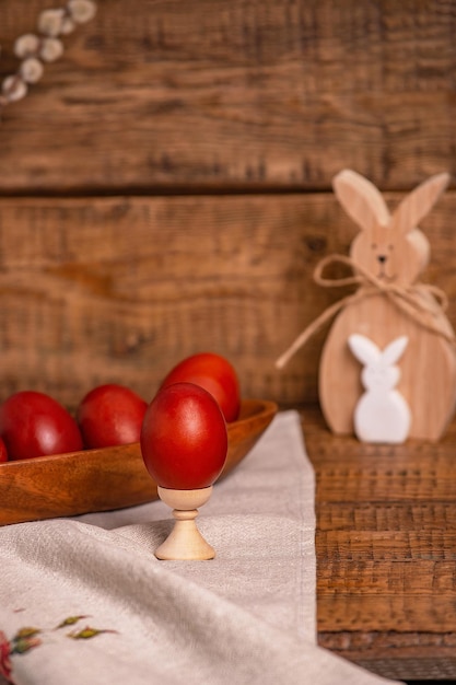 Auf einem hölzernen Hintergrund Ostereier, Zwiebelschalen und neben einem hölzernen Osterhasen und einer Weide