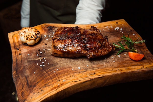 Auf einem Holzbrett liegt ein appetitliches, frisch zubereitetes gegrilltes Fleischsteak.