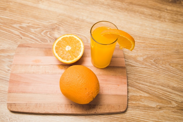 Auf einem Holztisch eine Orange und ein Glas mit einem Getränk