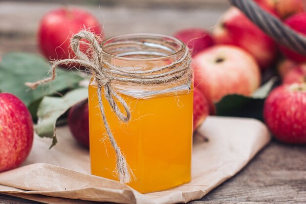 Auf einem Holztisch liegt ein Glas Honig und rote Äpfel. Herbsternte, Erntezeit, Herbststimmung und Rosh Hashanah