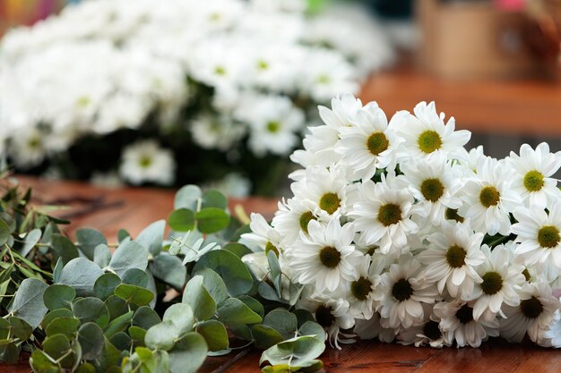 Auf einem Holztisch liegt ein Strauß weißer Chrysanthemen.