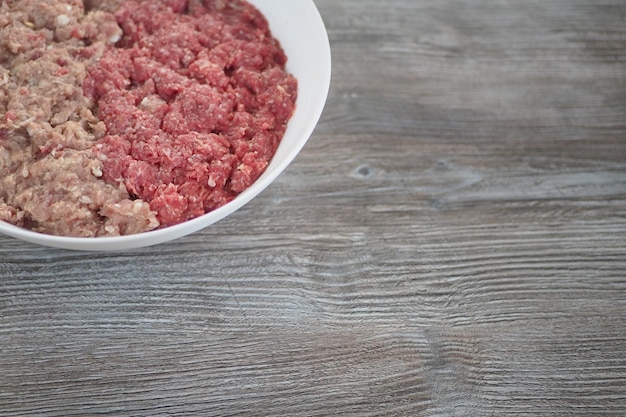 Foto auf einem holztisch steht eine schüssel hackfleisch.