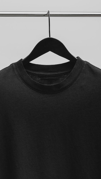 Auf einem Kleiderbügel hängt ein schwarzes T-Shirt mit schwarzem Kragen