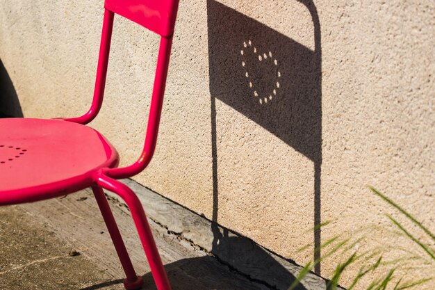 Auf einem Outdoor-Stuhl eingraviertes Herz mit einem lustigen Schatten, der vom Sonnenliebe-Konzept geworfen wird