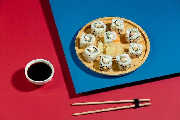 Auf einem rot-blauen Tisch steht ein Teller Sushi neben einer Tasse schwarzem Kaffee.