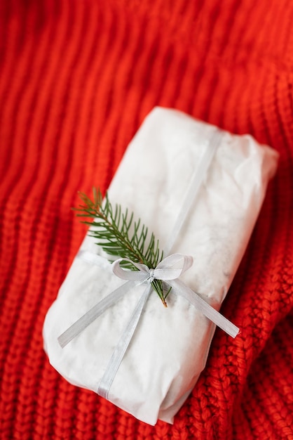 Auf einem roten Strickstoff liegt ein selbstgemachter Christstollen, eingeschweißt in weißes Bastelpapier. Geschenkpapier.