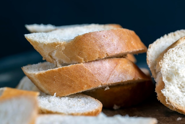 Auf einem Schneidebrett in Stücke geschnittenes Weizenbaguette Weißes Weizenbaguette wird während des Garens in Scheiben geschnitten