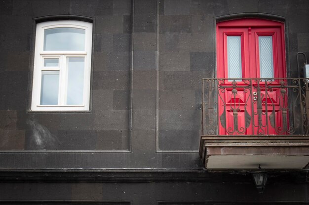 Auf einem schwarzen Haus eine rote Tür und ein weißes Fenster