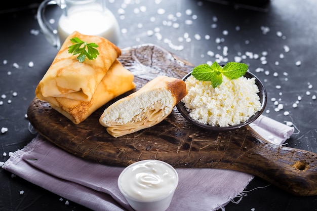 Foto auf einem teller pfannkuchen mit hüttenkäse, kirschtomaten, besteck auf schwarzem, isoliertem hintergrund,