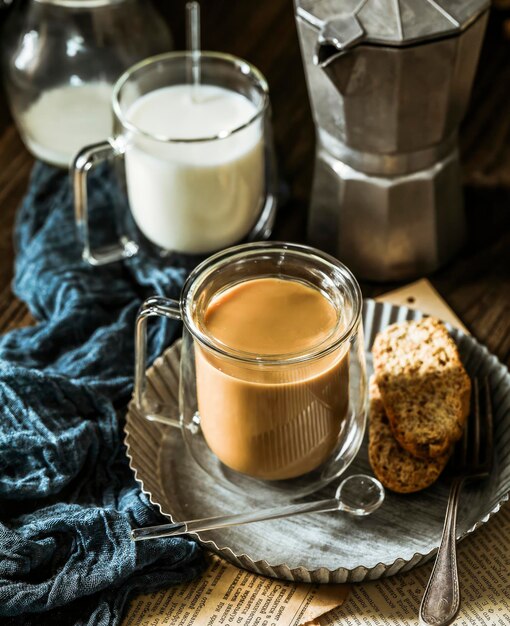 Auf einem Teller steht eine Glastasse Kaffee neben einem Glas Milch. Entspannung bei Milchkaffee