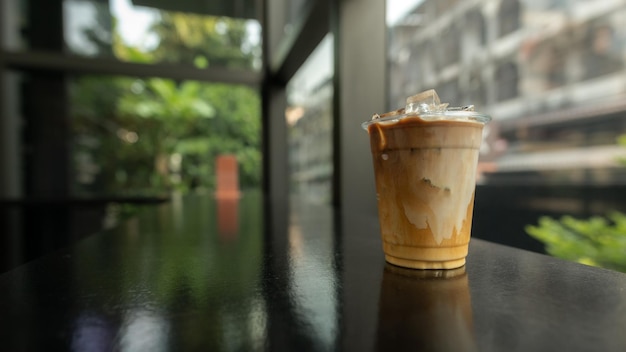 Auf einem Tisch in einem Café steht eine Tasse Eiskaffee mit einem durchsichtigen Plastikbecher