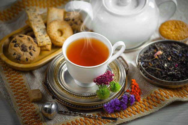 Auf einem Tisch steht eine Tasse Tee mit einer Schüssel Kekse und einer Schüssel Tee.