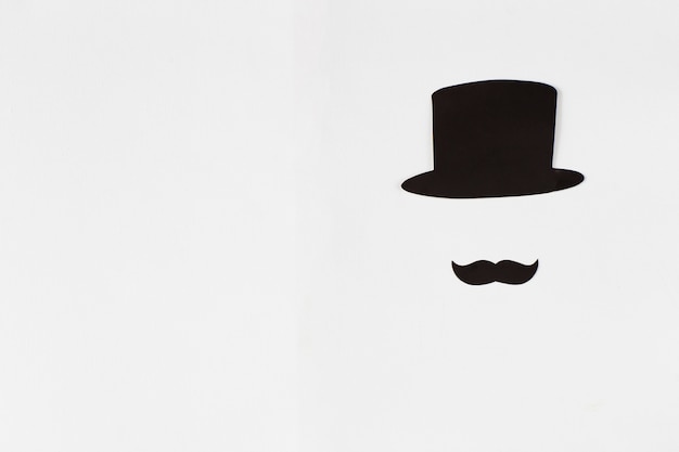 Auf einem weißen Hintergrund schwarzer Schnurrbart und schwarzer Zylinder - Hintergrund eines Gentlemans