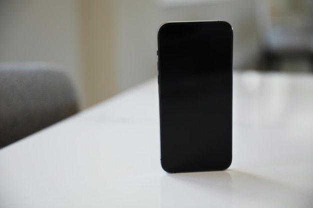 Auf einem weißen Tisch liegt ein schwarzes Handy.