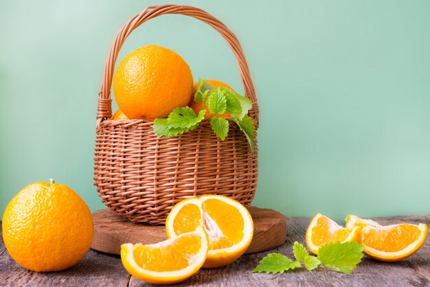 Auf einer Holzwand steht ein Weidenkorb mit Orangen und Mandarinen. Horizontales Foto.