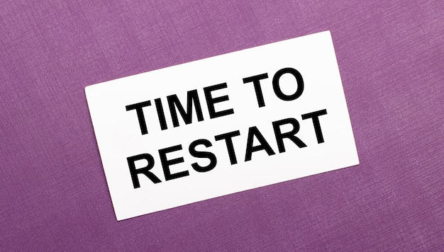 Auf einer lila Oberfläche eine weiße Karte mit den Worten TIME TO RESTART