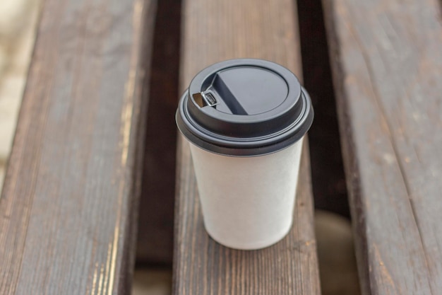 Auf einer Parkbank steht ein Pappbecher mit Kaffee