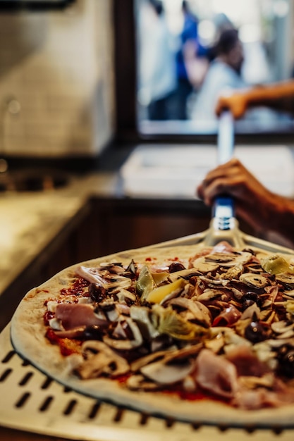 Foto auf einer pizzaschaufel wird eine pizza mit blauem griff zubereitet.