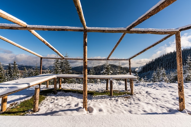 Auf einer schneebedeckten weißen Wiese steht ein großer, nicht überdachter Pavillon auf dem Gipfel des Berges