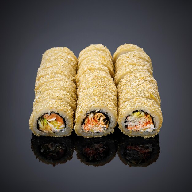 Auf einer schwarzen Fläche sind vier Sushi-Rollen aufgereiht.