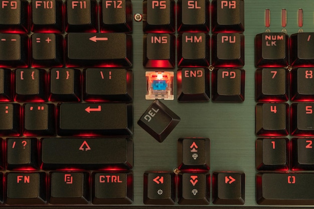 Auf einer schwarzen Tastatur mit roter Hintergrundbeleuchtung ist die Löschtaste kaputt und liegt neben ihrem Platz