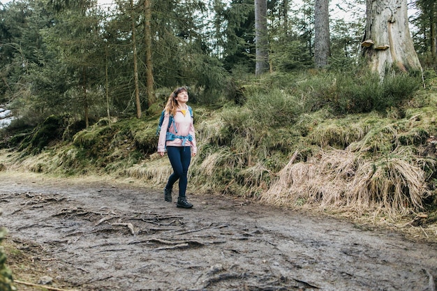 Auf einer Wanderung im Freien geht eine junge Touristin mit Rucksack durch den Wald und genießt die Natur