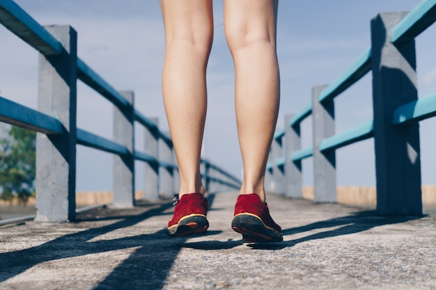 Auf grünem hintergrund geht und läuft eine frau mit laufschuhen. bewegung für die gesundheit ist ein begriff.