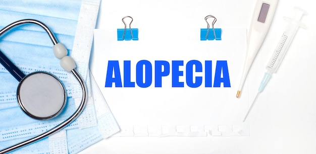 Auf hellem Hintergrund sind Medikamente und ein Blatt Papier mit der Aufschrift ALOPECIA