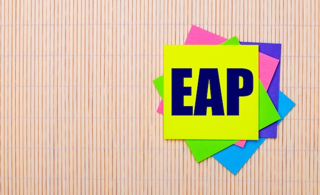 Auf hellem Holzhintergrund leuchtend bunte Aufkleber mit dem Text EAP Employee Assistance Program