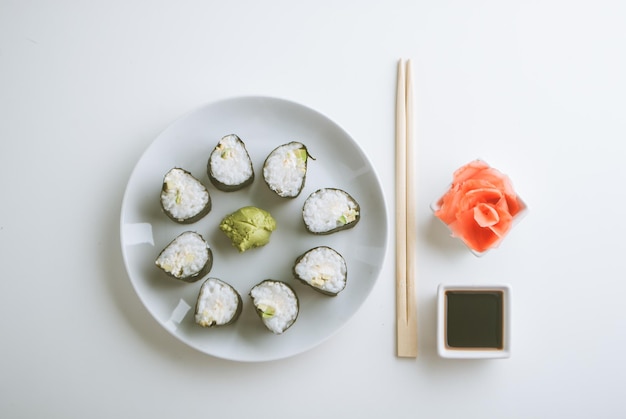 Aufbau von vegetarischen Sushi-Rollen aus Avocado und Gurke mit Ingwer-Wasabi und Sojasauce