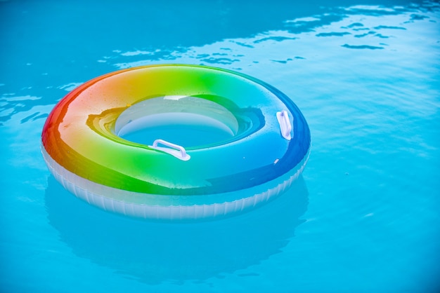 Aufblasbarer Ring, der im blauen Swimmingpool schwimmt. Sommer Hintergrund.