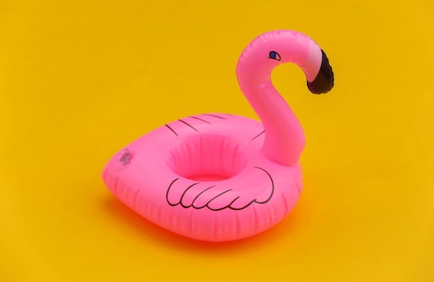 Aufblasbarer rosa Flamingo auf gelbem Hintergrund. Sommerferienkonzept.