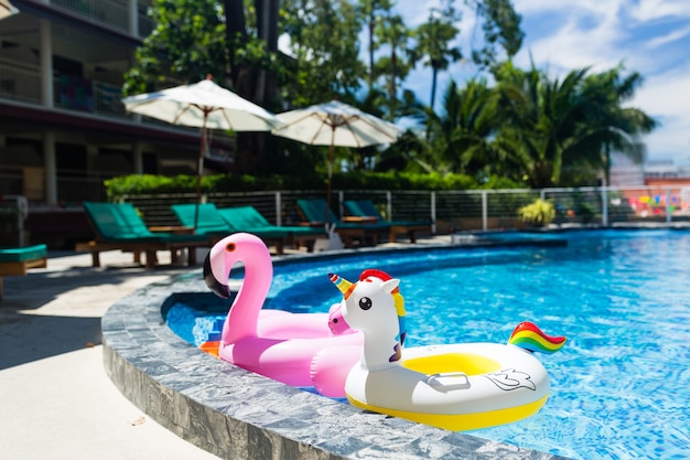 Aufblasbares buntes weißes Einhorn und rosa Flamingo am Swimmingpool.