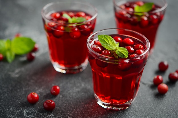 Auffrischungscocktail mit Moosbeere und Minze auf dunklem konkretem Hintergrund.