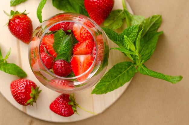 Auffrischungserdbeerwasser oder Limonade verziert mit tadellosen Blättern auf hölzernem Brett